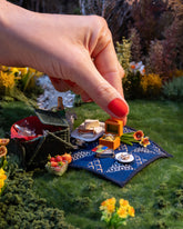 Styled image of the Luna Ring Charm, with the Daffodil Charm, California Poppy Charm, Stick of Salted Butter Charm, Sardine Can Charm, Sardine Fish Charm, Saltine Charm and Caviar Charm on model.