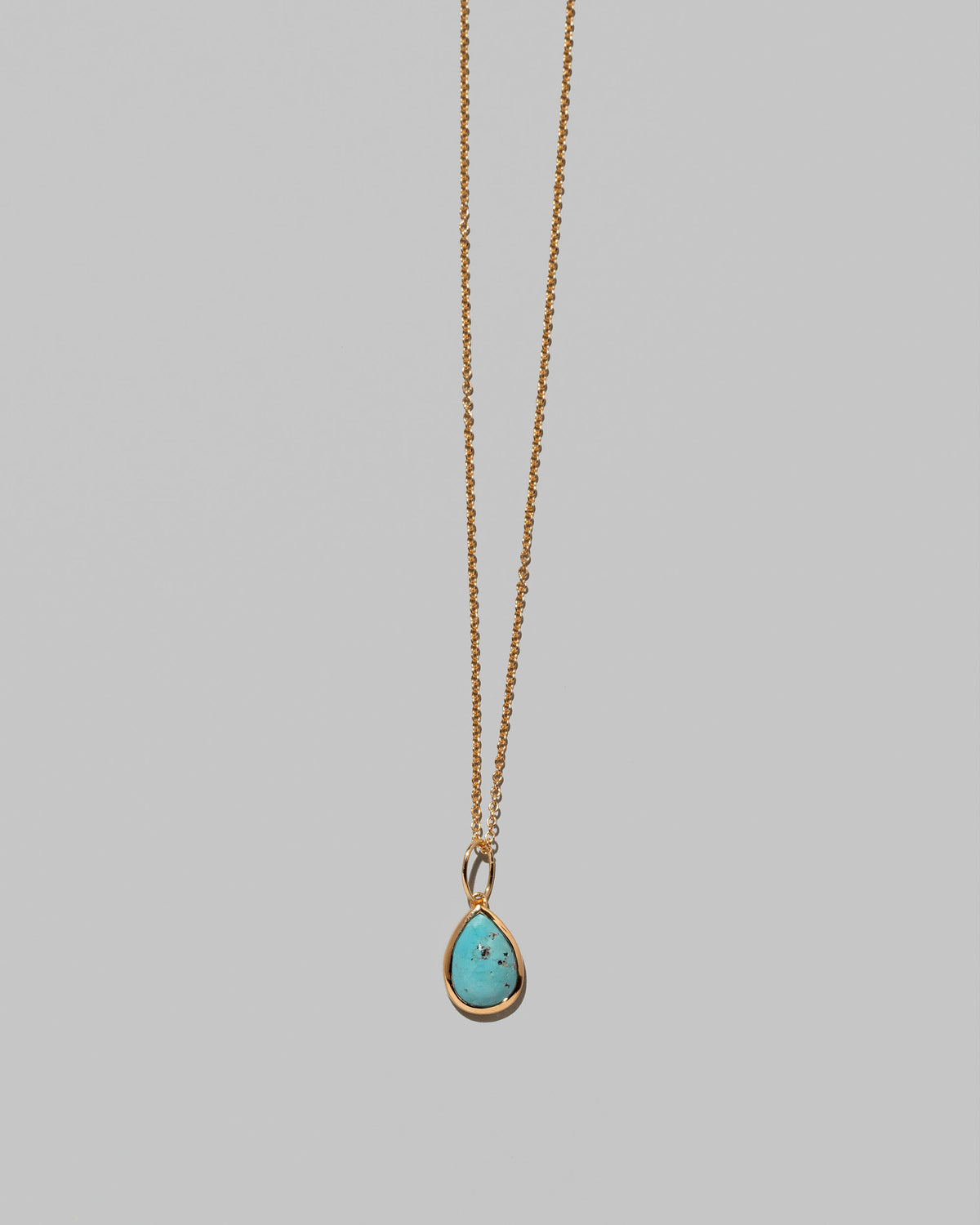 Closeup details of the State Shifter Turquoise Pendant paired with chain on light color background.