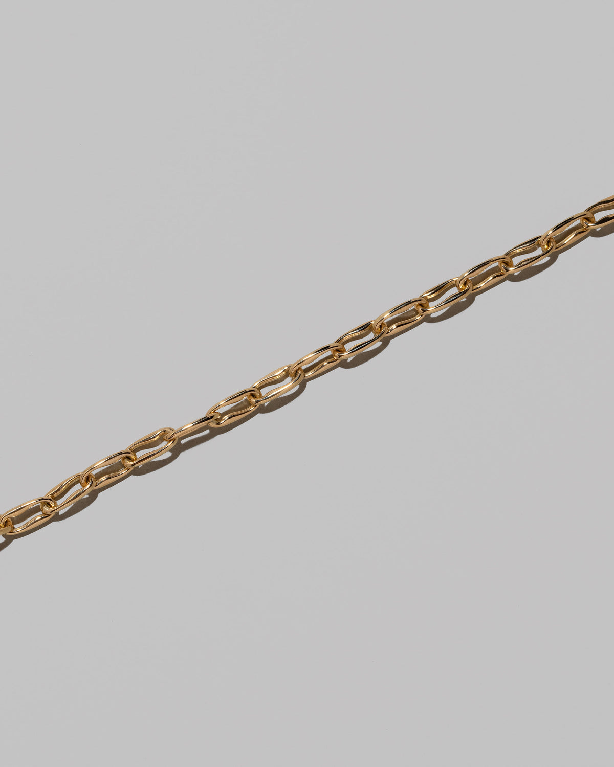 Closeup details of the Wavy Link Chain Necklace on light color background.