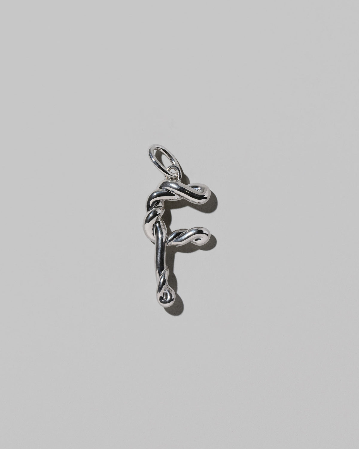 CRZM Sterling Silver Letter F Bag Charm on light color background.