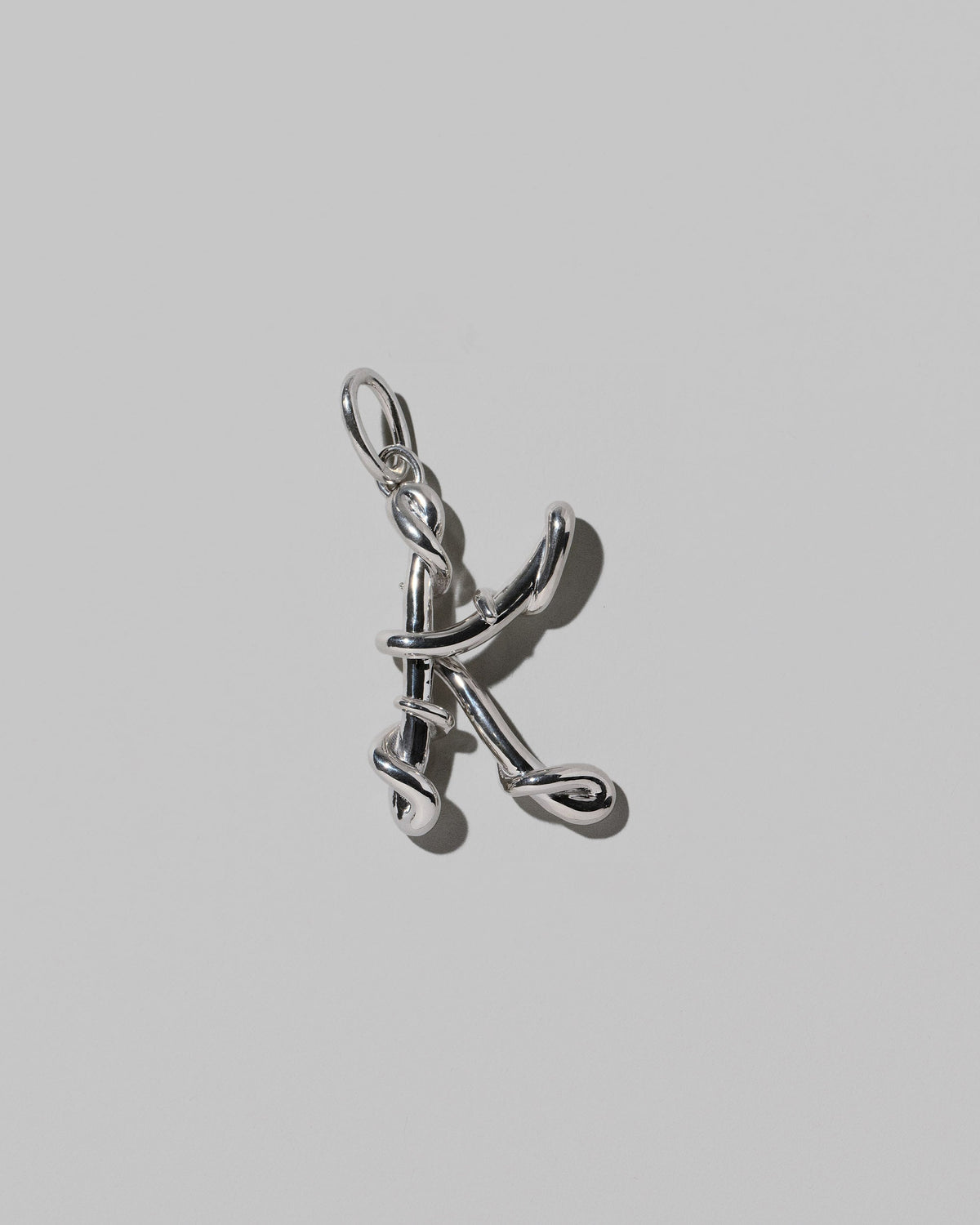 CRZM Sterling Silver Letter K Bag Charm on light color background.