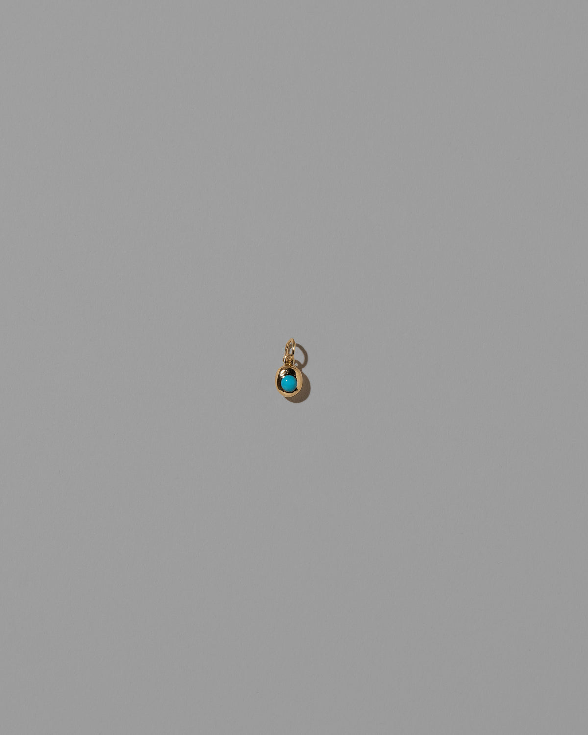 Turquoise Cabochon Birthstone Level Charm on light color background.