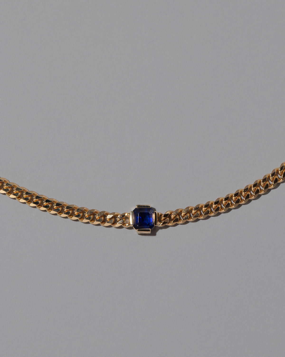 Closeup details of the Blue Sapphire Fold Necklace on grey color background.