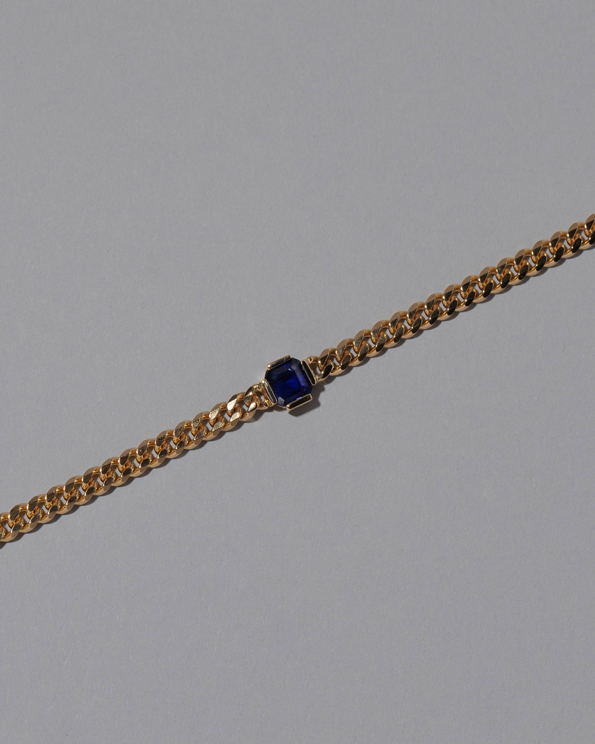 Closeup details of the Gold Blue Sapphire Fold Bracelet on grey color background.