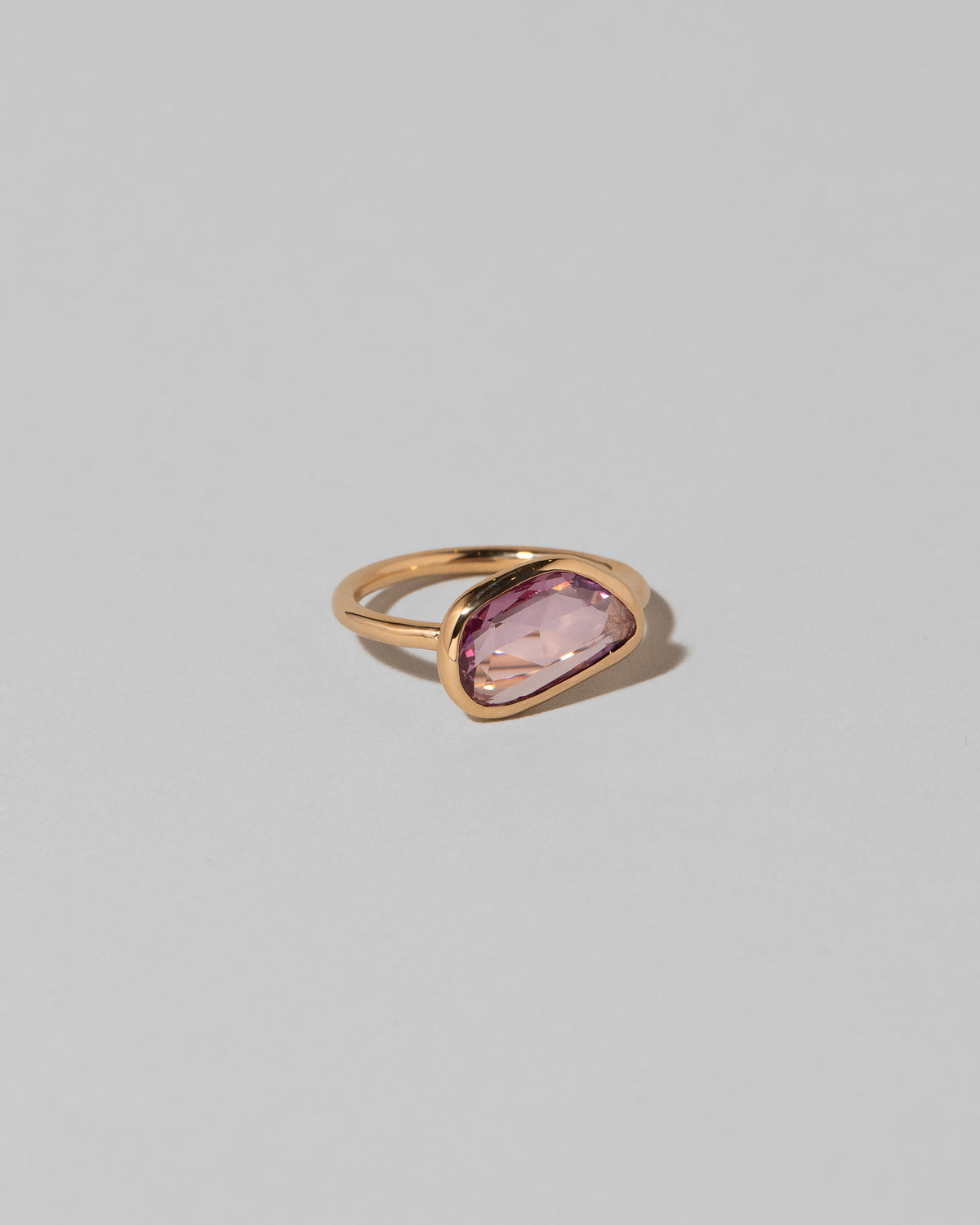 View from the side of the Gusher Pink Sapphire Ring 011 on light color background.