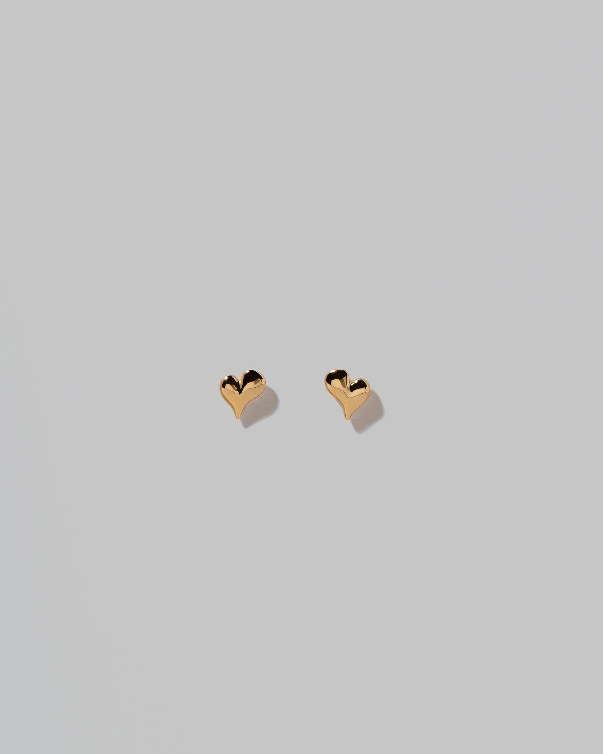Shape Two Small Thousand & One Night Heart Stud Earrings on light color background.
