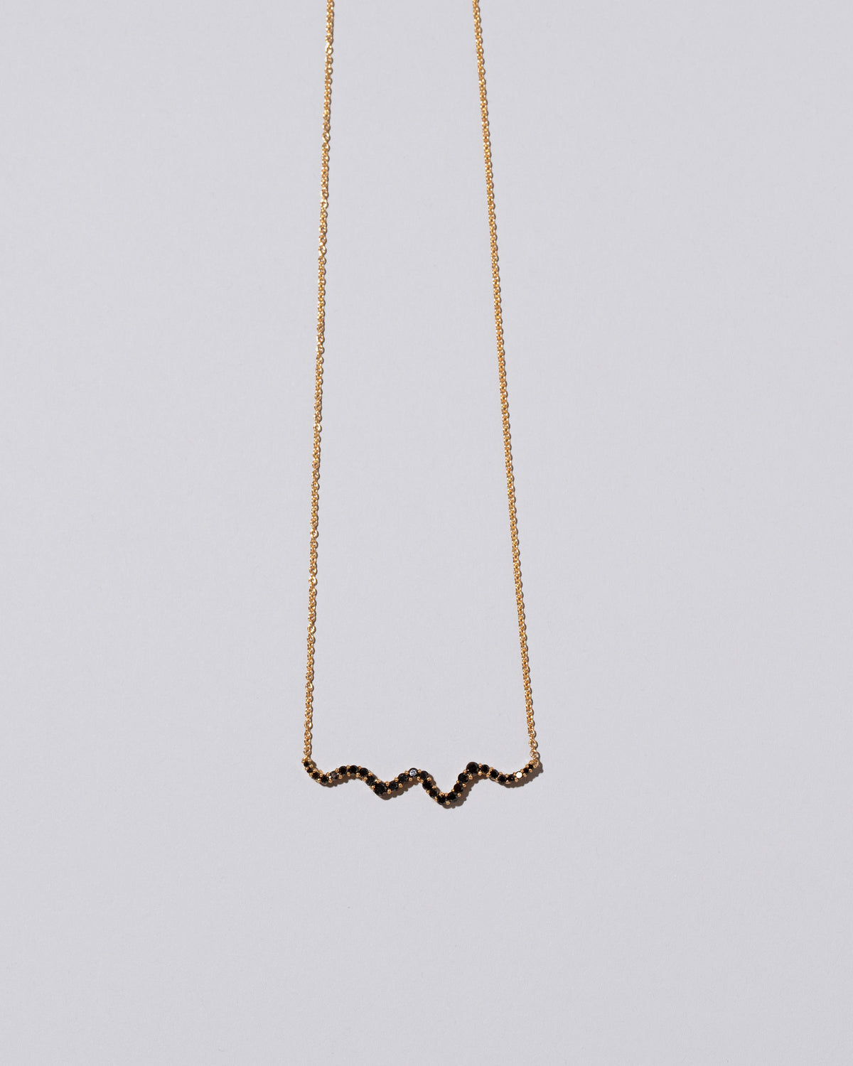 Closeup detail of the Black Diamond Ripple Wave Necklace on light color background.