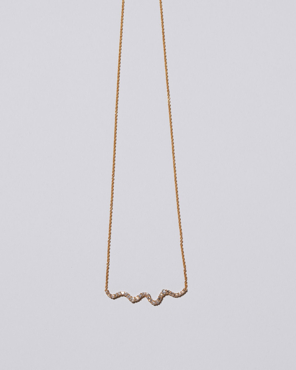 Closeup detail of the White Diamond Ripple Wave Necklace on light color background.