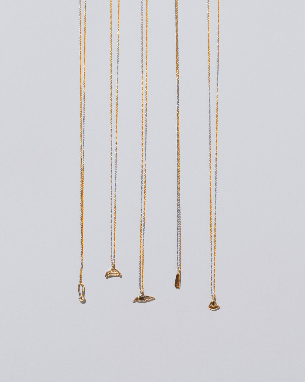 Group of Water, Eye, Foot, Lotus Blossom and Loop & Sphere Talisman Pendant Necklaces on light color background.