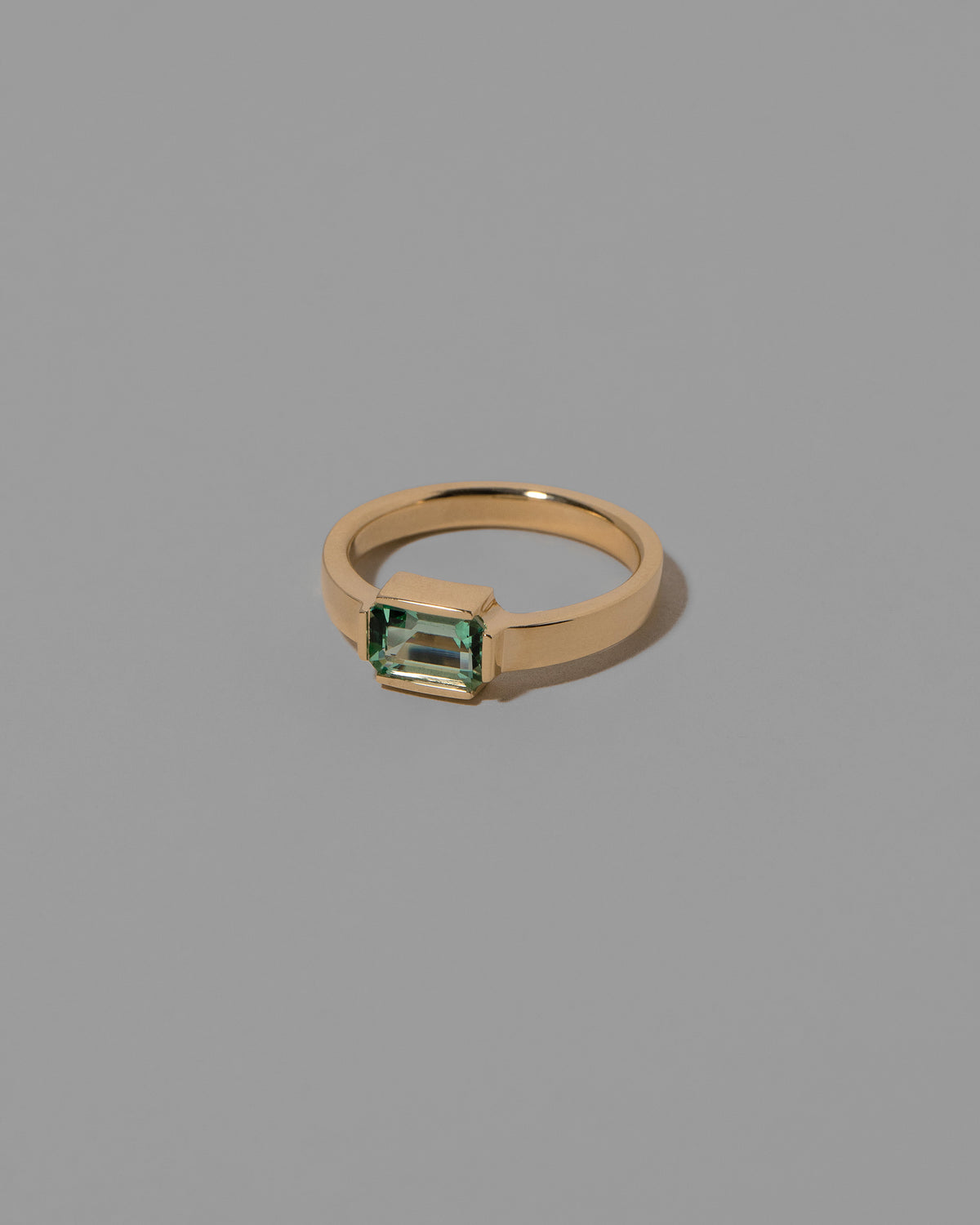 View from the side of the Emerald Fold Ring on light color background.
