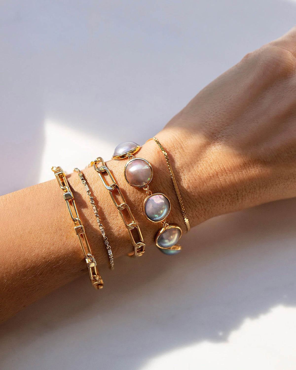Serpentina Chain Bracelet, Loon Mabe Pearl Bracelet, Lightweight Long Oval Link Bracelet, Full White Diamond Building Blocks Bracelet and Lightweight Half Loop Link Bracelet on model.