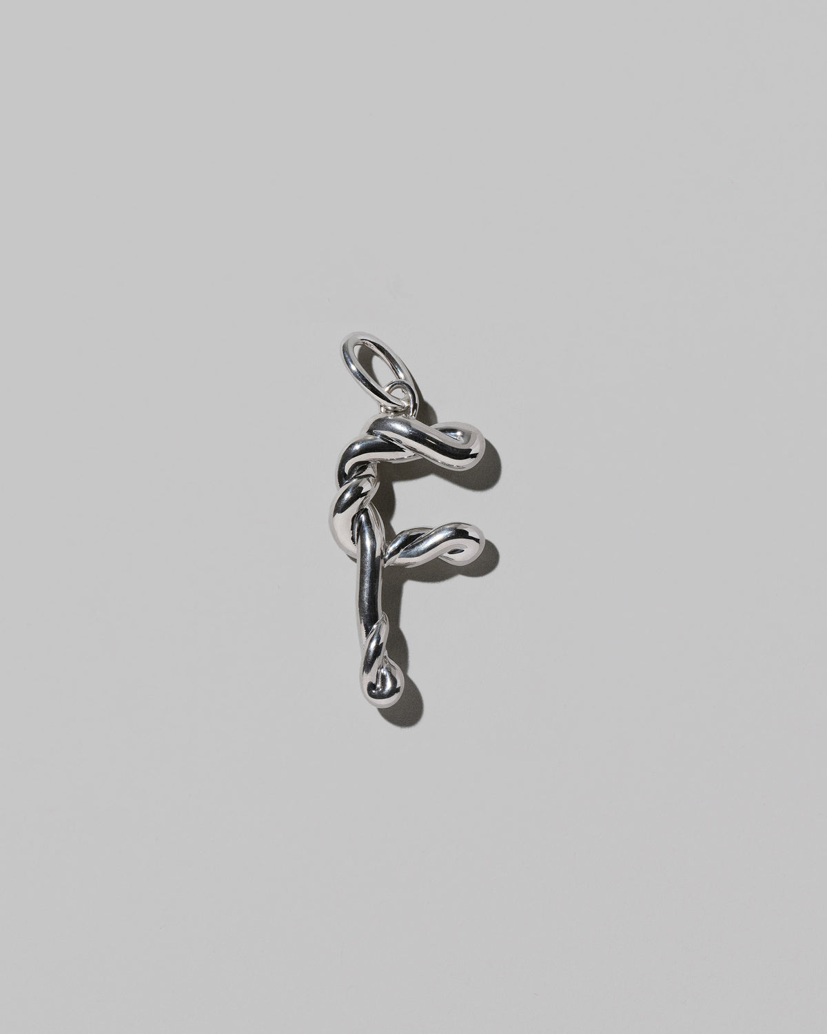 CRZM Large Letter F Charm set in sterling silver on light color background.