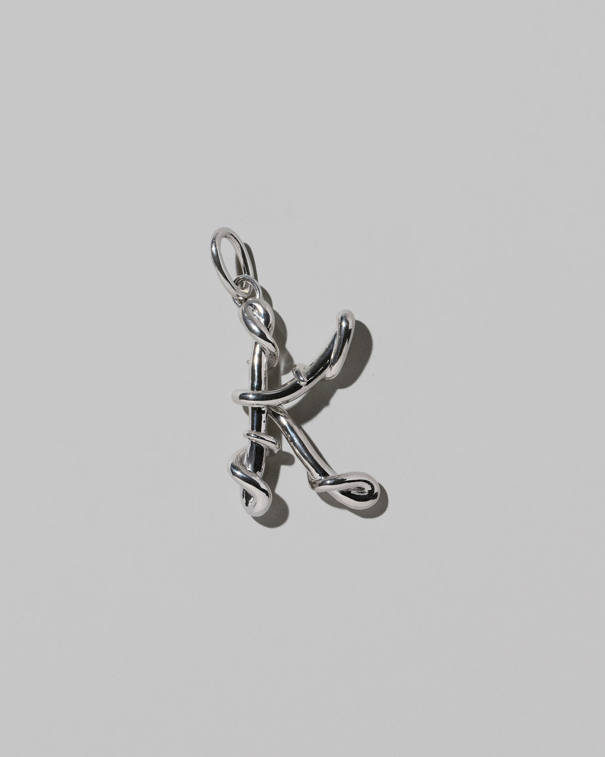 CRZM Large Letter K Charm set in sterling silver on light color background.