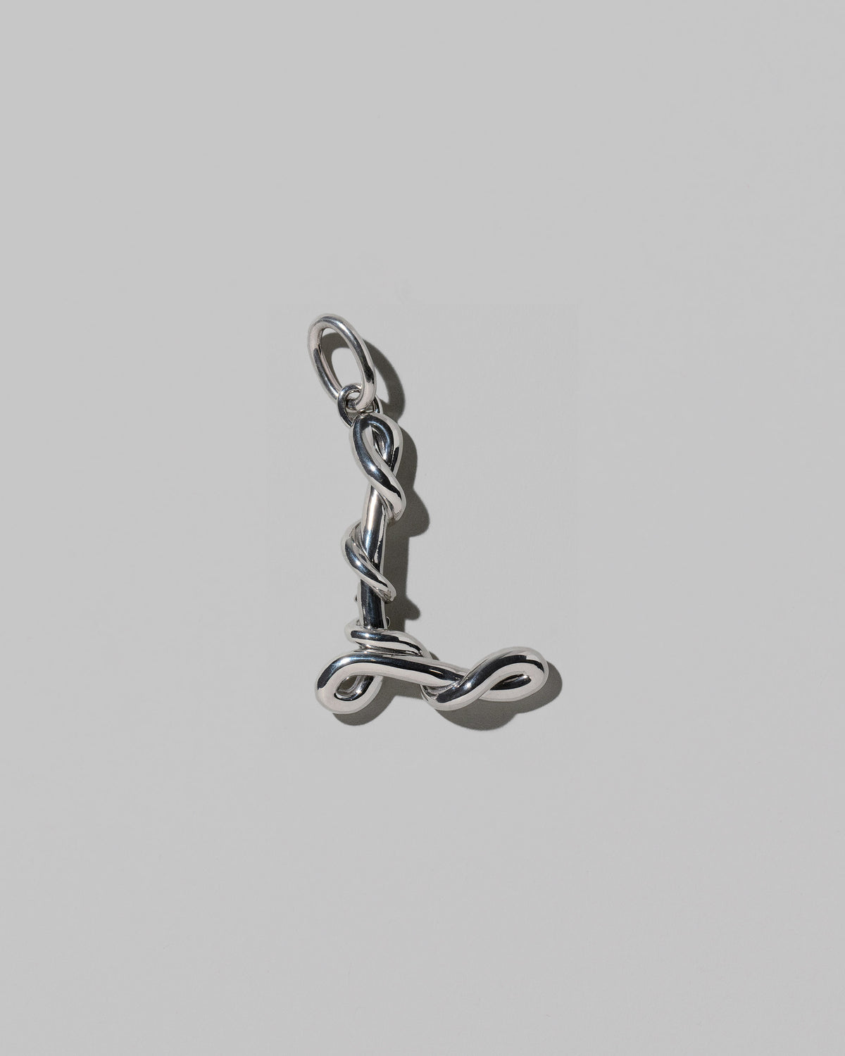 CRZM Large Letter L Charm set in sterling silver on light color background.