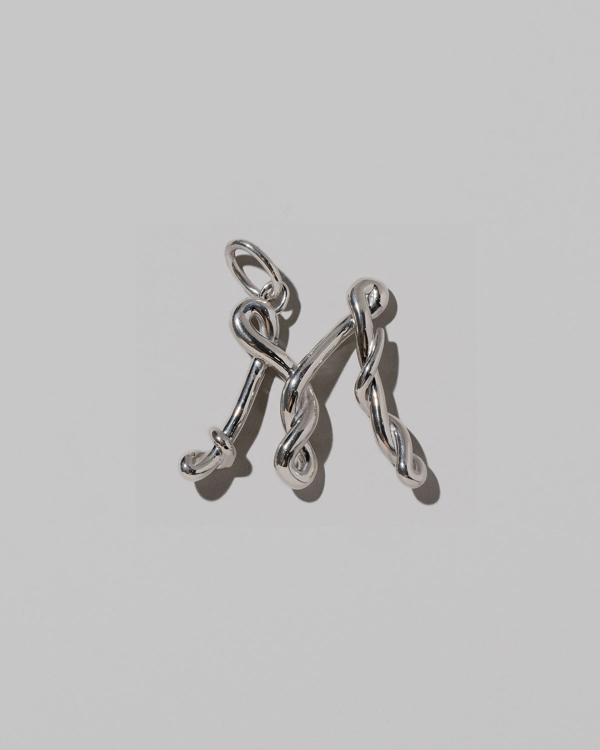 CRZM Large Letter M Charm set in sterling silver on light color background.