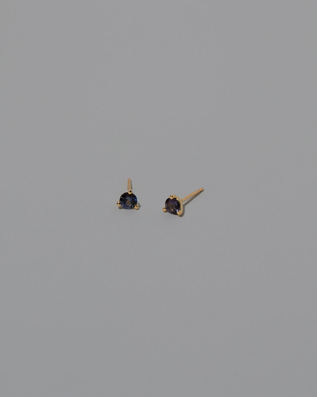 Purple Sapphire Martini Stud Earrings on light color background.