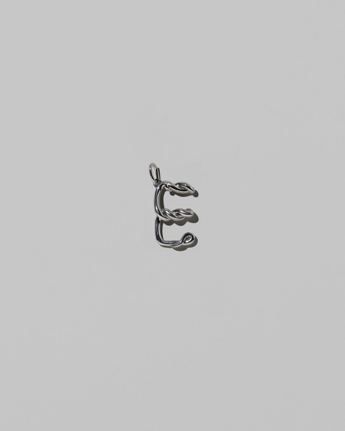 CRZM Medium Letter E Charm set in sterling silver on light color background.