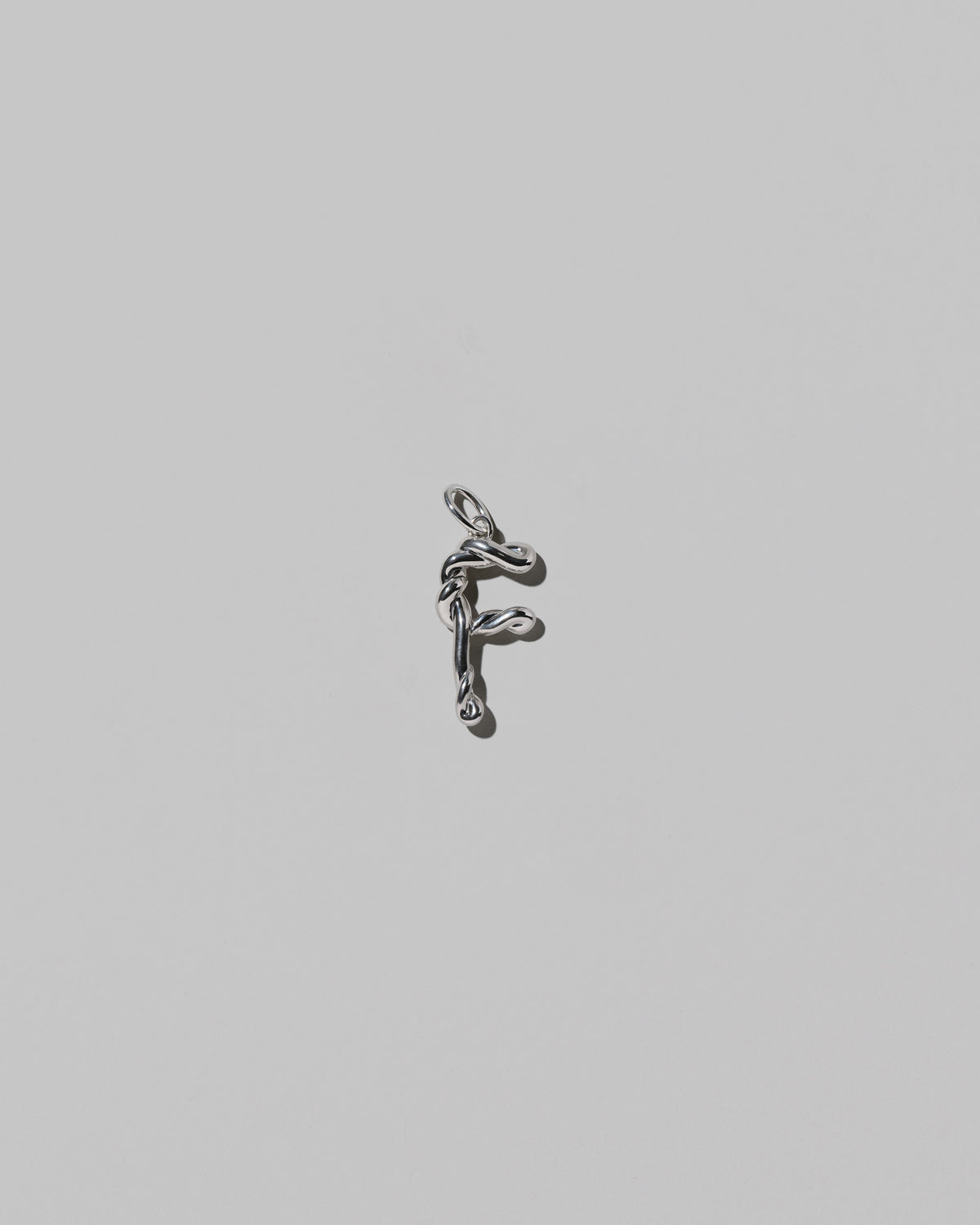 CRZM Medium Letter F Charm set in sterling silver on light color background.