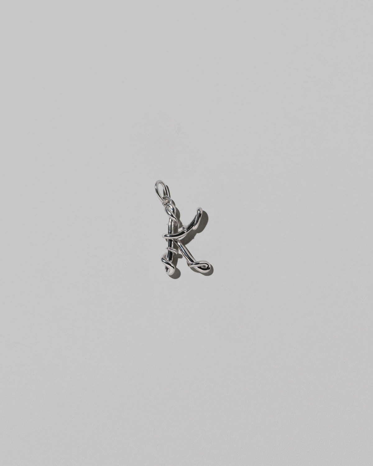CRZM Medium Letter K Charm set in sterling silver on light color background.