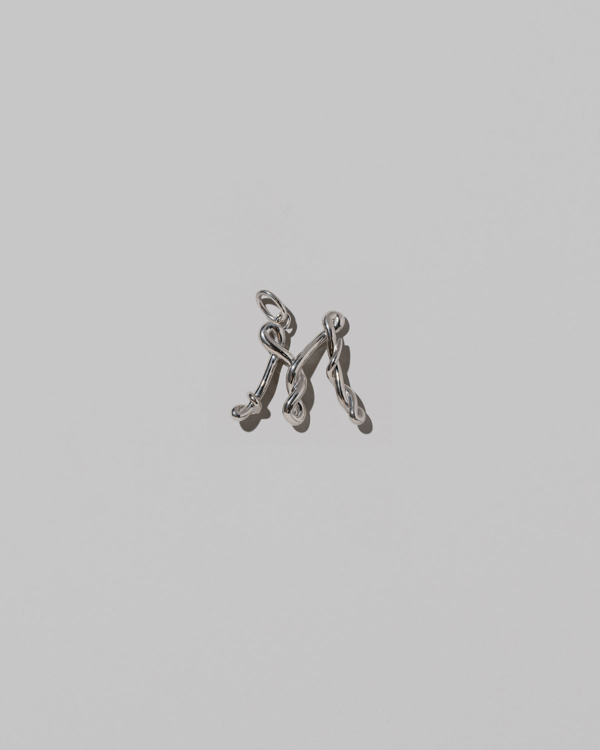 CRZM Medium Letter M Charm set in sterling silver on light color background.
