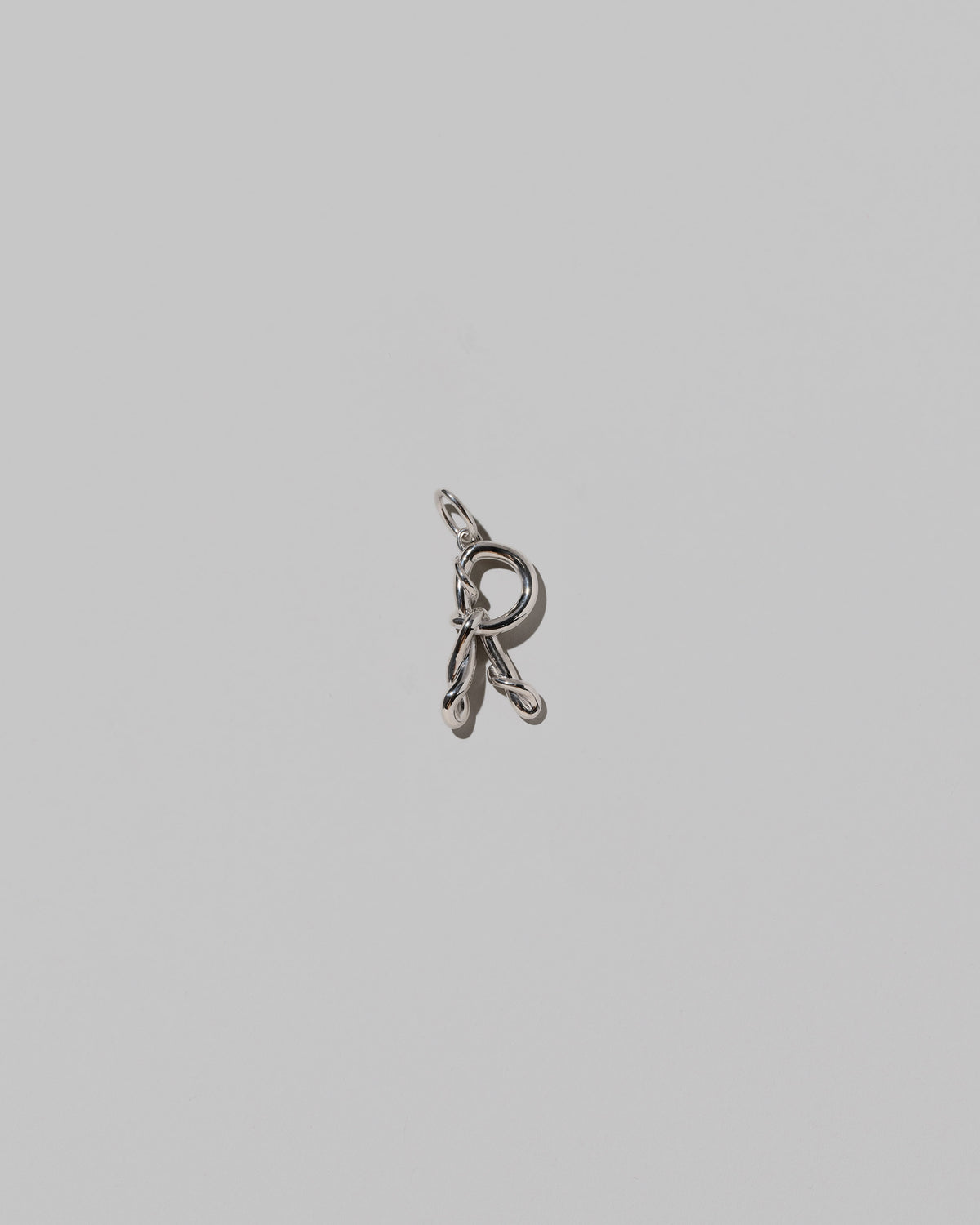 CRZM Medium Letter R Charm set in sterling silver on light color background.