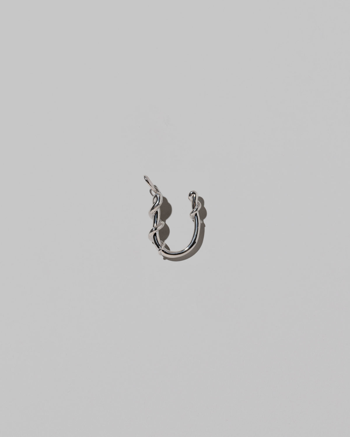 CRZM Medium Letter U Charm set in sterling silver on light color background.