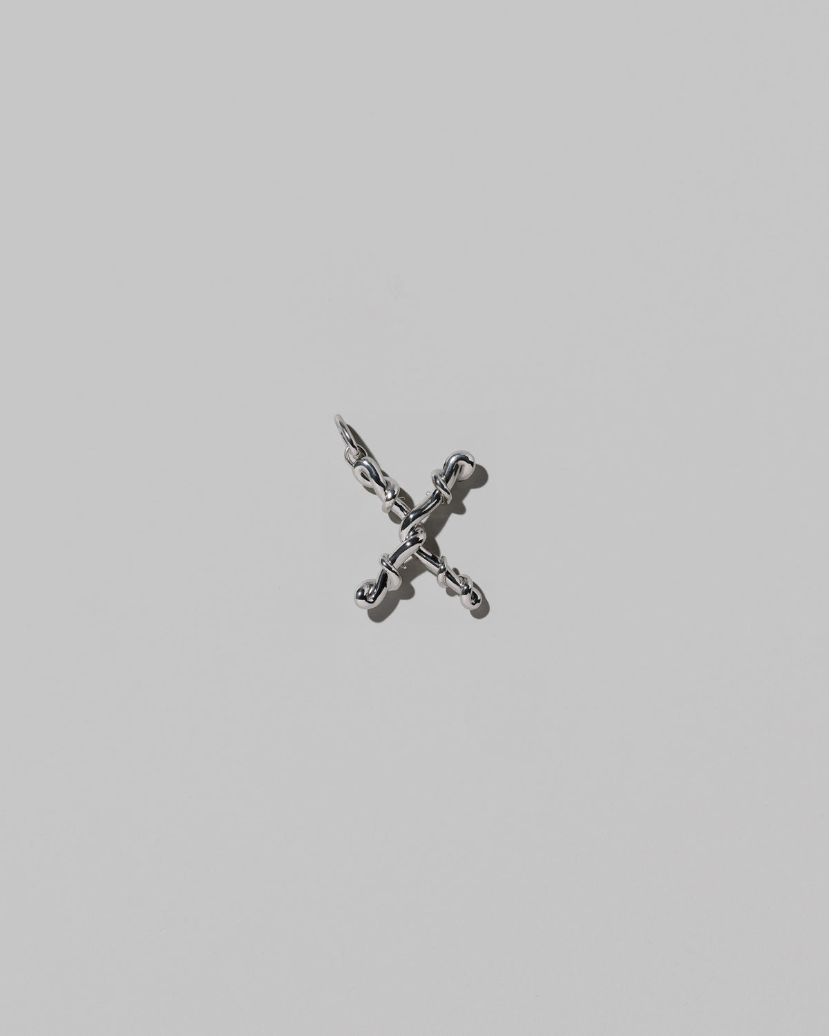 CRZM Medium Letter X Charm set in sterling silver on light color background.
