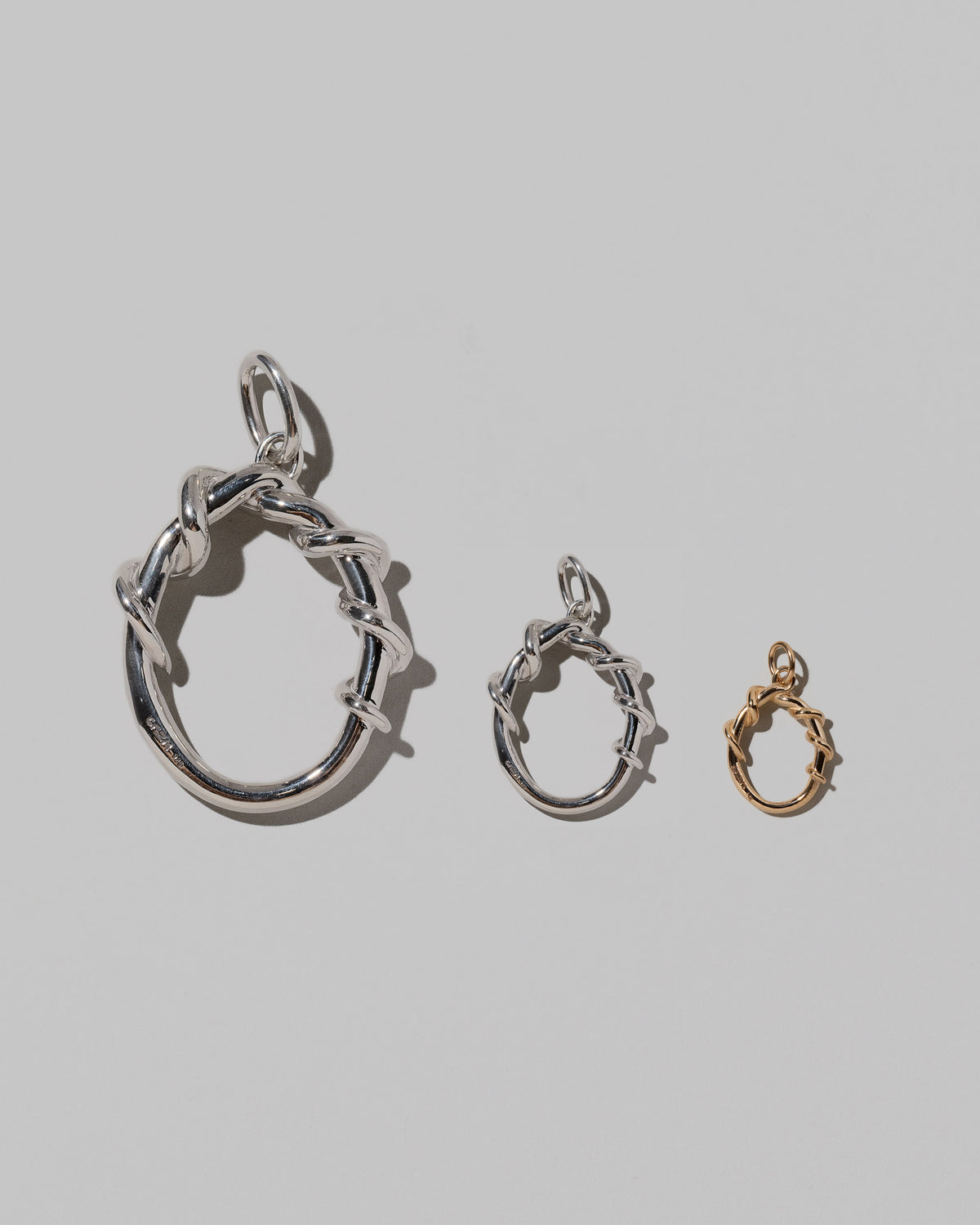 CRZM Large Sterling Silver, Medium Sterling Silver & Mini Letter O Charms set in solid gold on light color background.