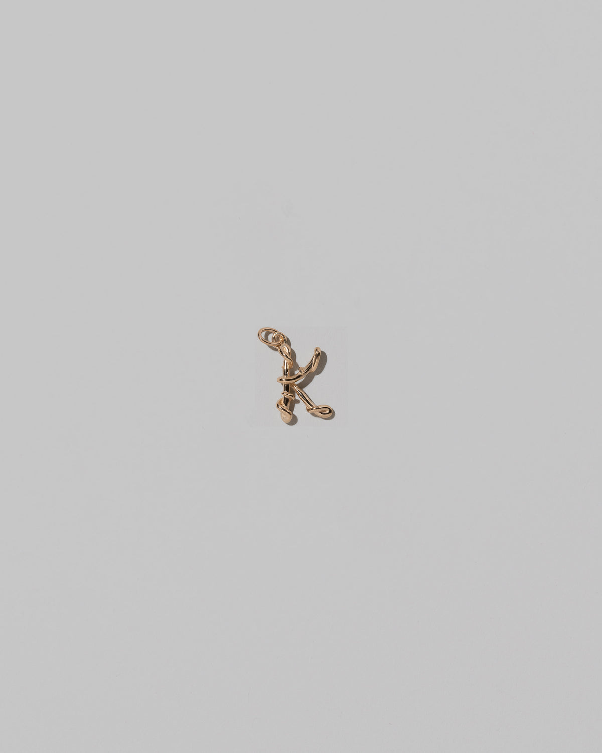 CRZM Mini Letter K set in solid gold on light color background.