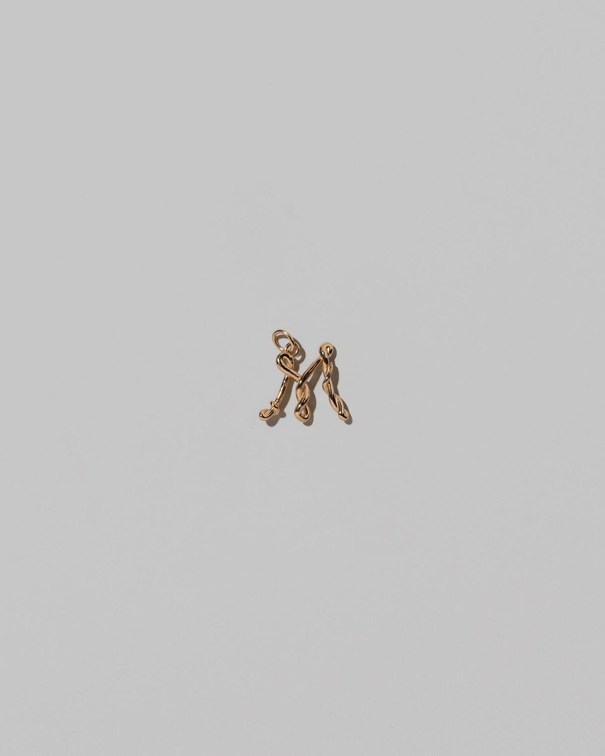 CRZM Mini Letter M set in solid gold on light color background.
