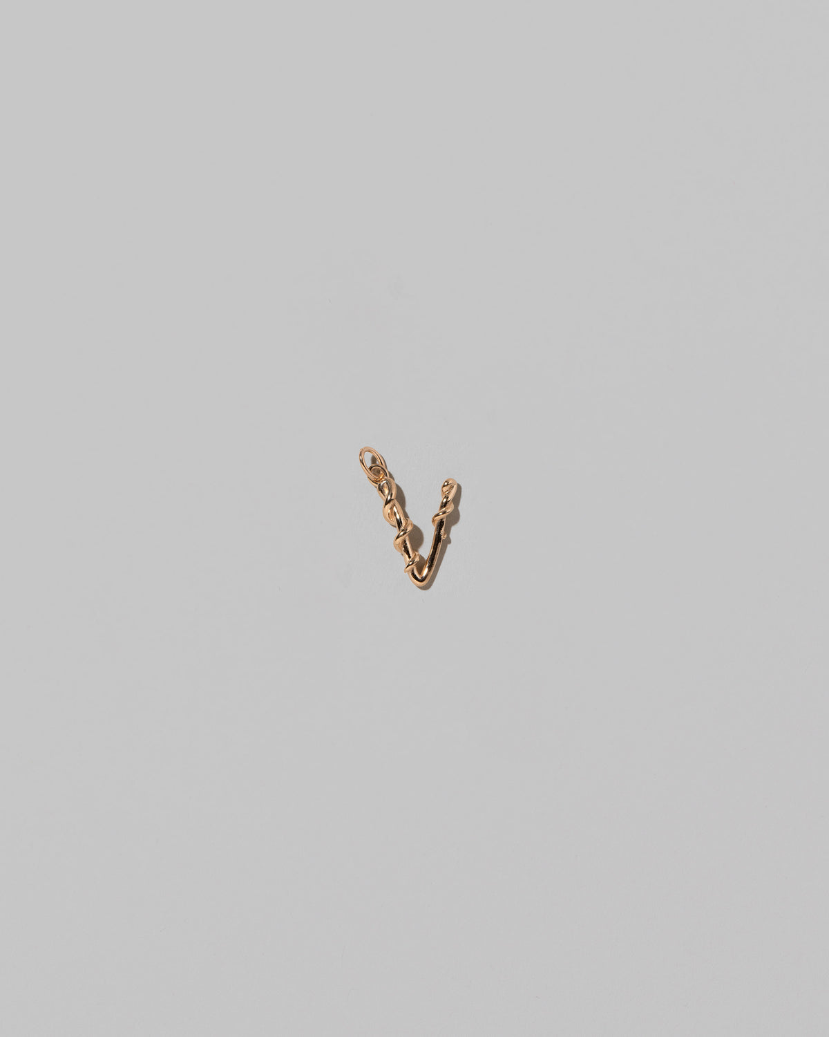 CRZM Mini Letter V set in solid gold on light color background.