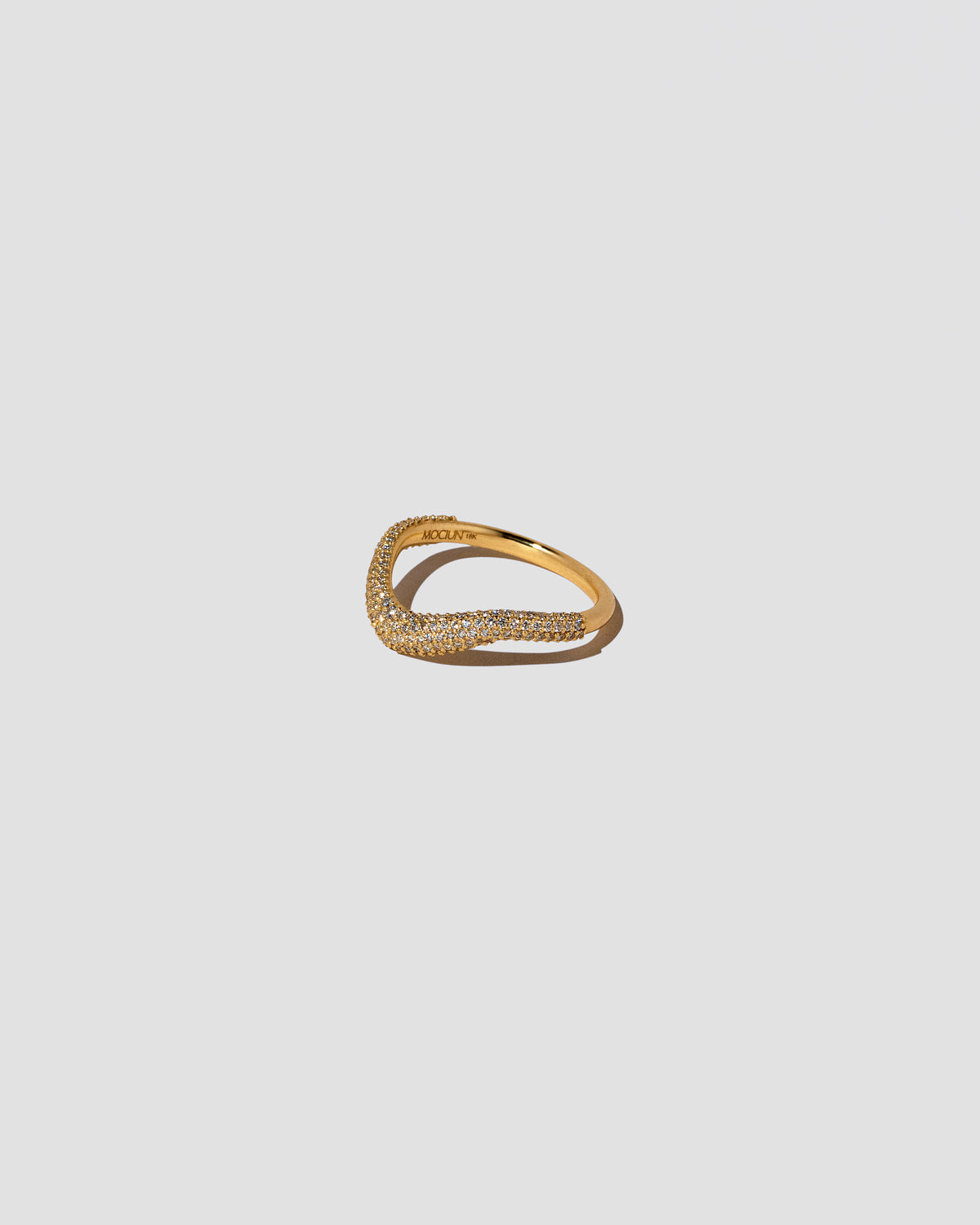 View from the side of the Gold Pavé Thin Level Band on light color background.