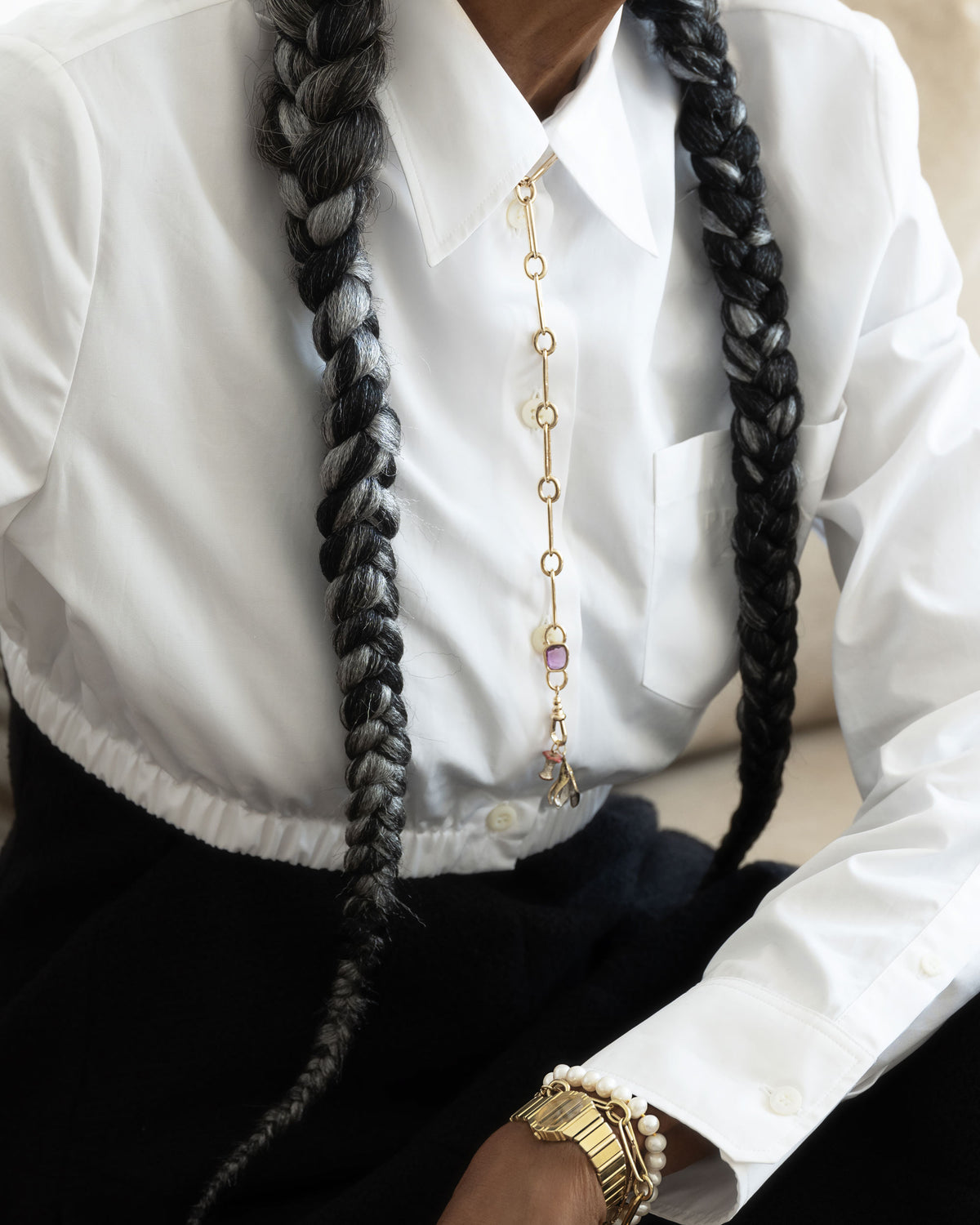 Styled image on model featuring the Sapphire Gusher Openable Pendant connected to a closed-loop oval link of the Link Necklace worn as a lariat, and a Bruised Banana Peel Charm and Red Apple Core Charm suspended from its Gold Coiled Swivel Charm Holder clasp.