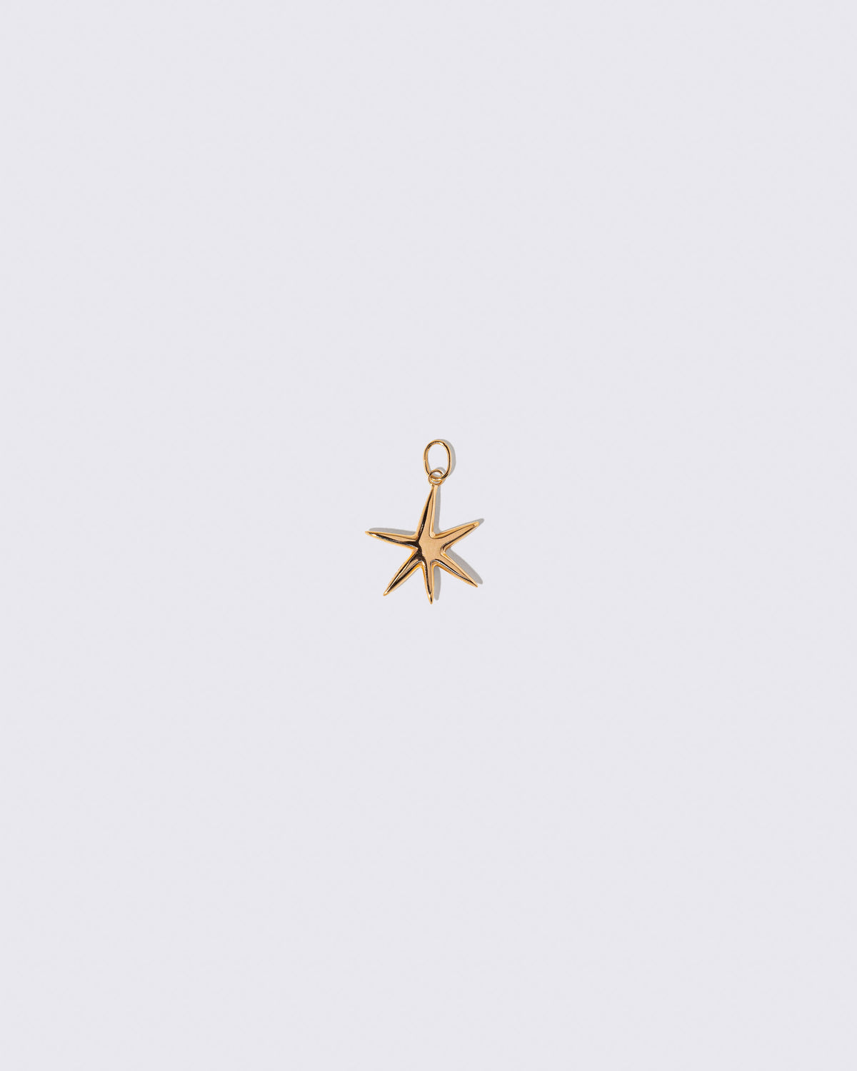 Gold Grand Verve Six Point Star Charm on light color background.