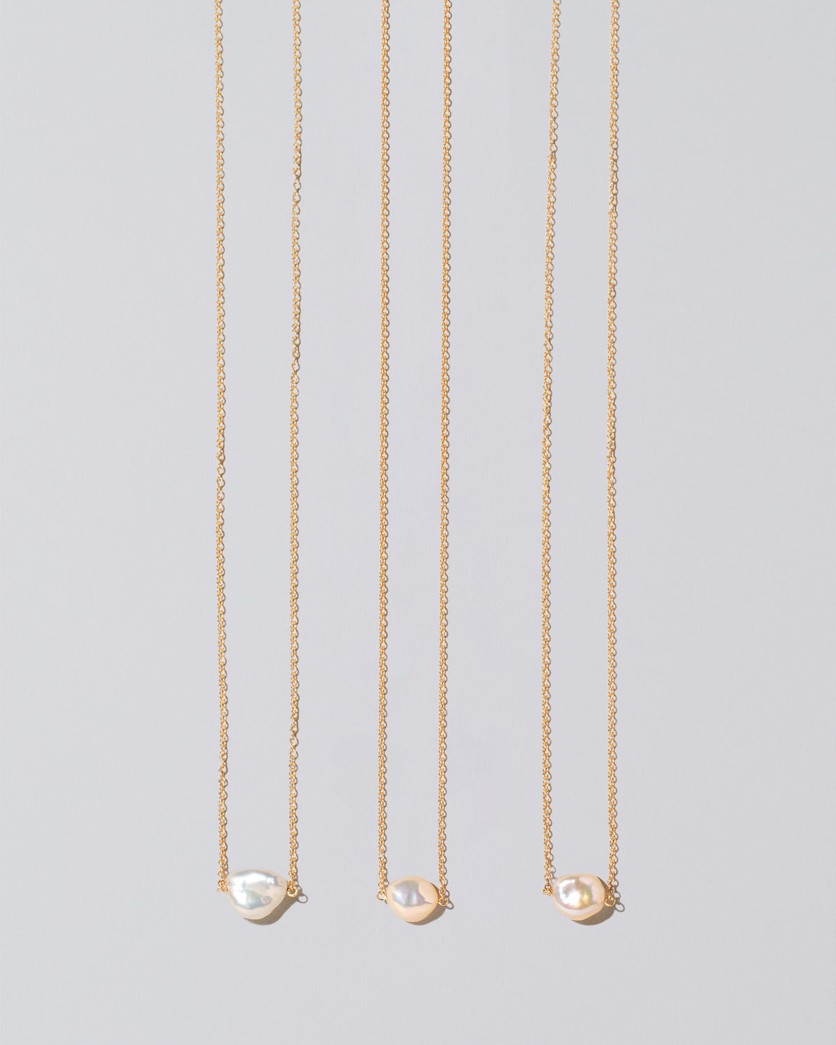 Group of the White Lagniappe Pearl Necklaces on light color background.