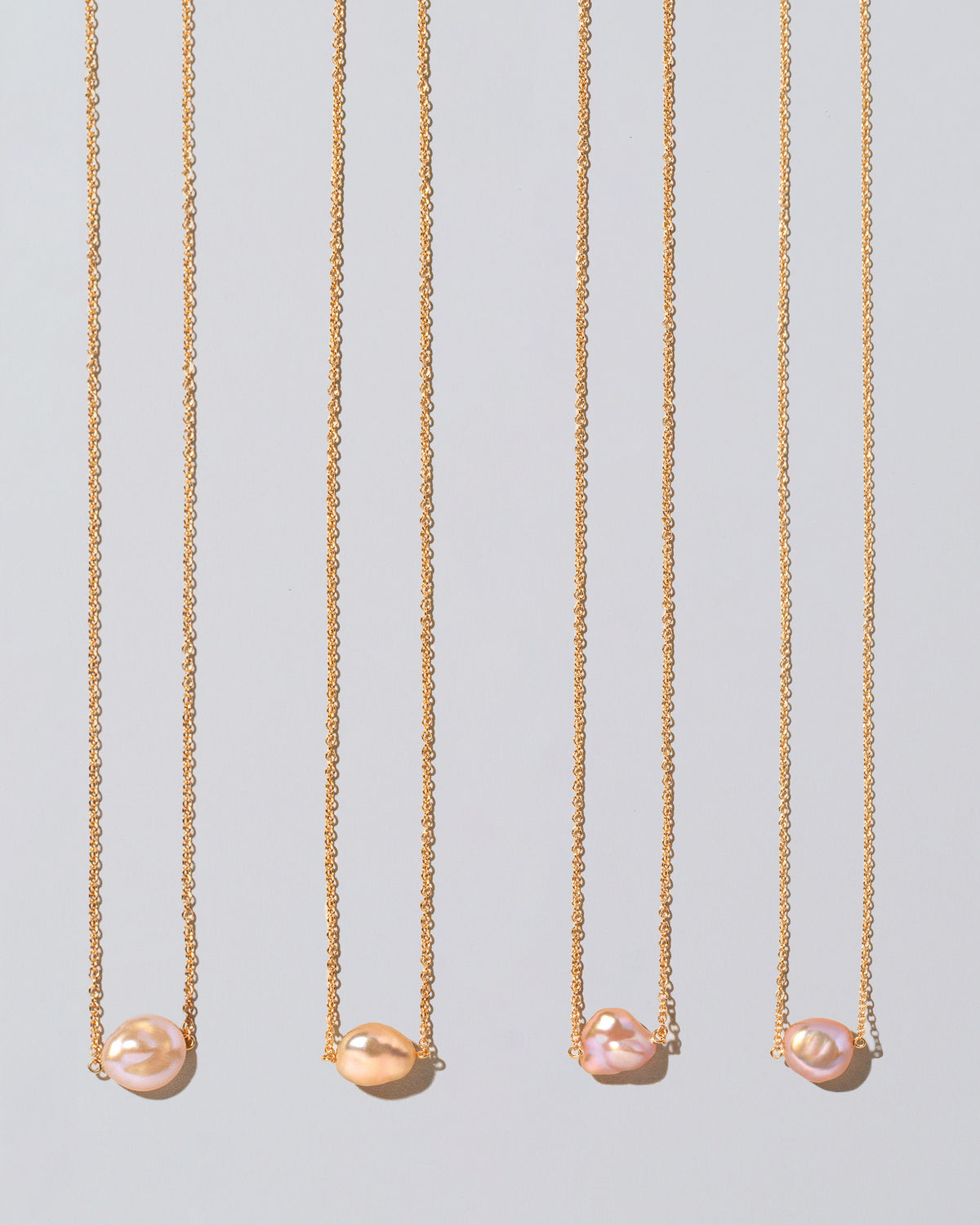 Group of Blush Pink Lagniappe Pearl Necklaces on light color background.