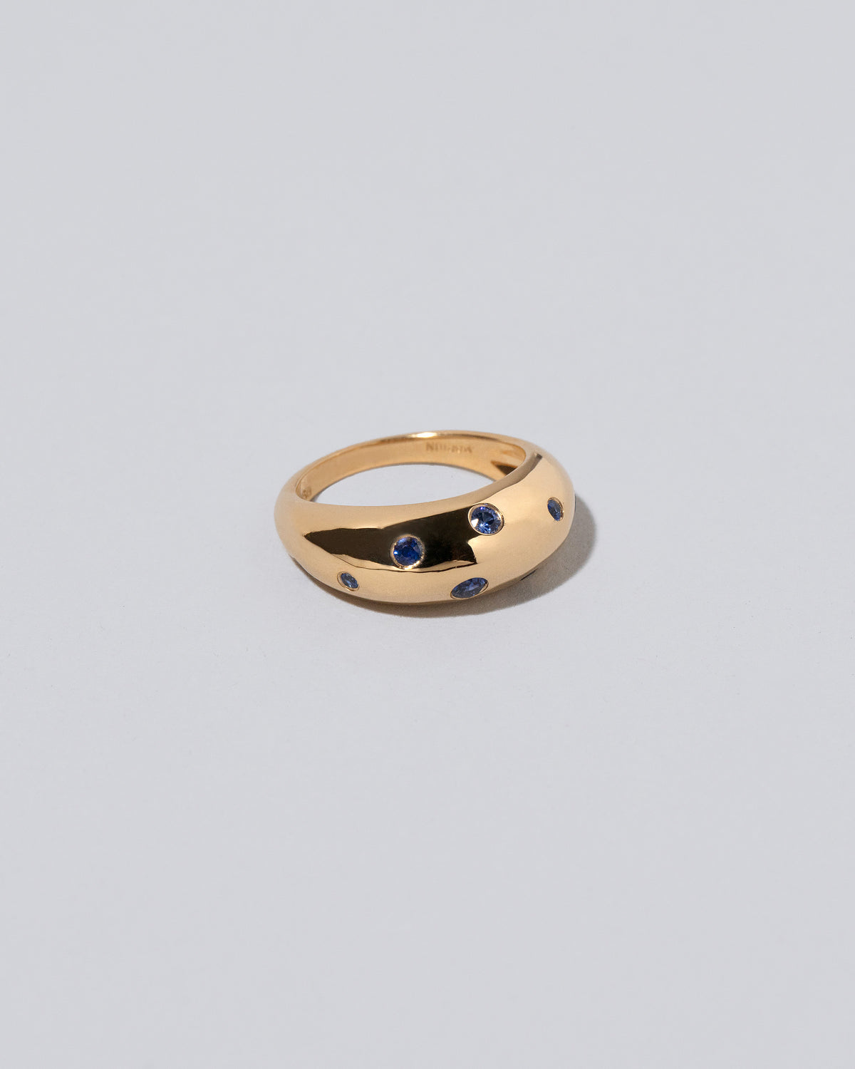 Closeup details of the Gold Blue Sapphire Brilliant Cuts Light Cutter Band on light color background.