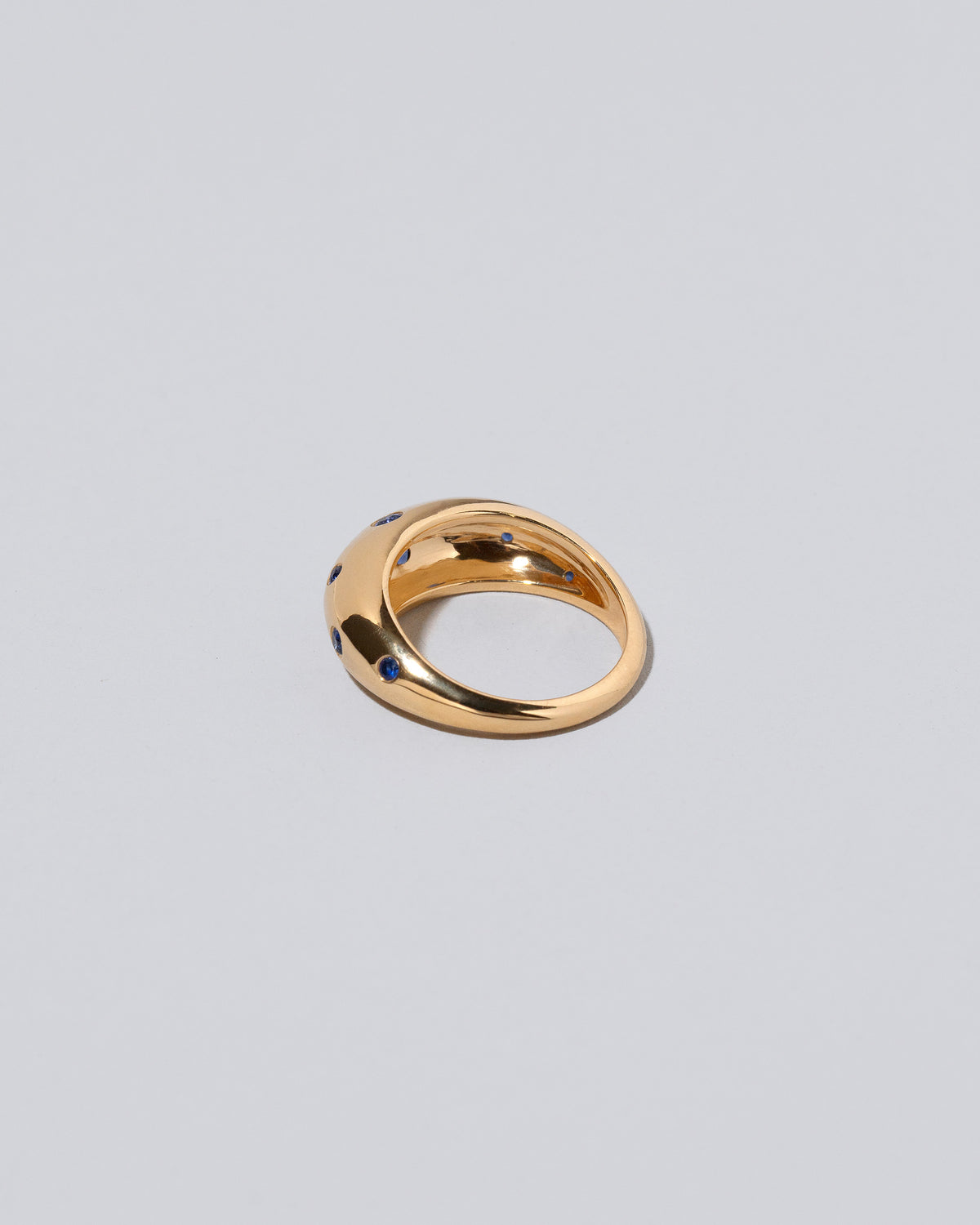 View from the back of the Gold Blue Sapphire Brilliant Cuts Light Cutter Band on light color background.