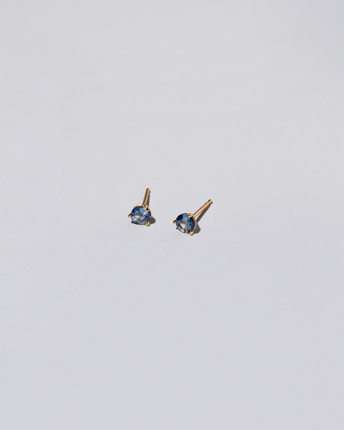 Blue Bicolor Sapphire Martini Stud Earrings on light color background.