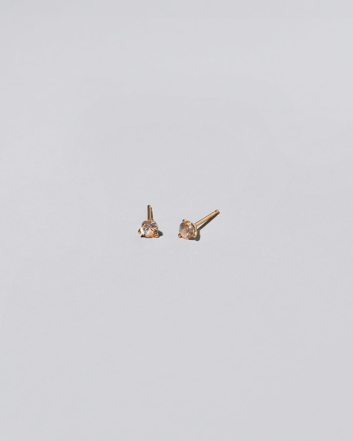 Peach Sapphire Martini Stud Earrings on light color background.
