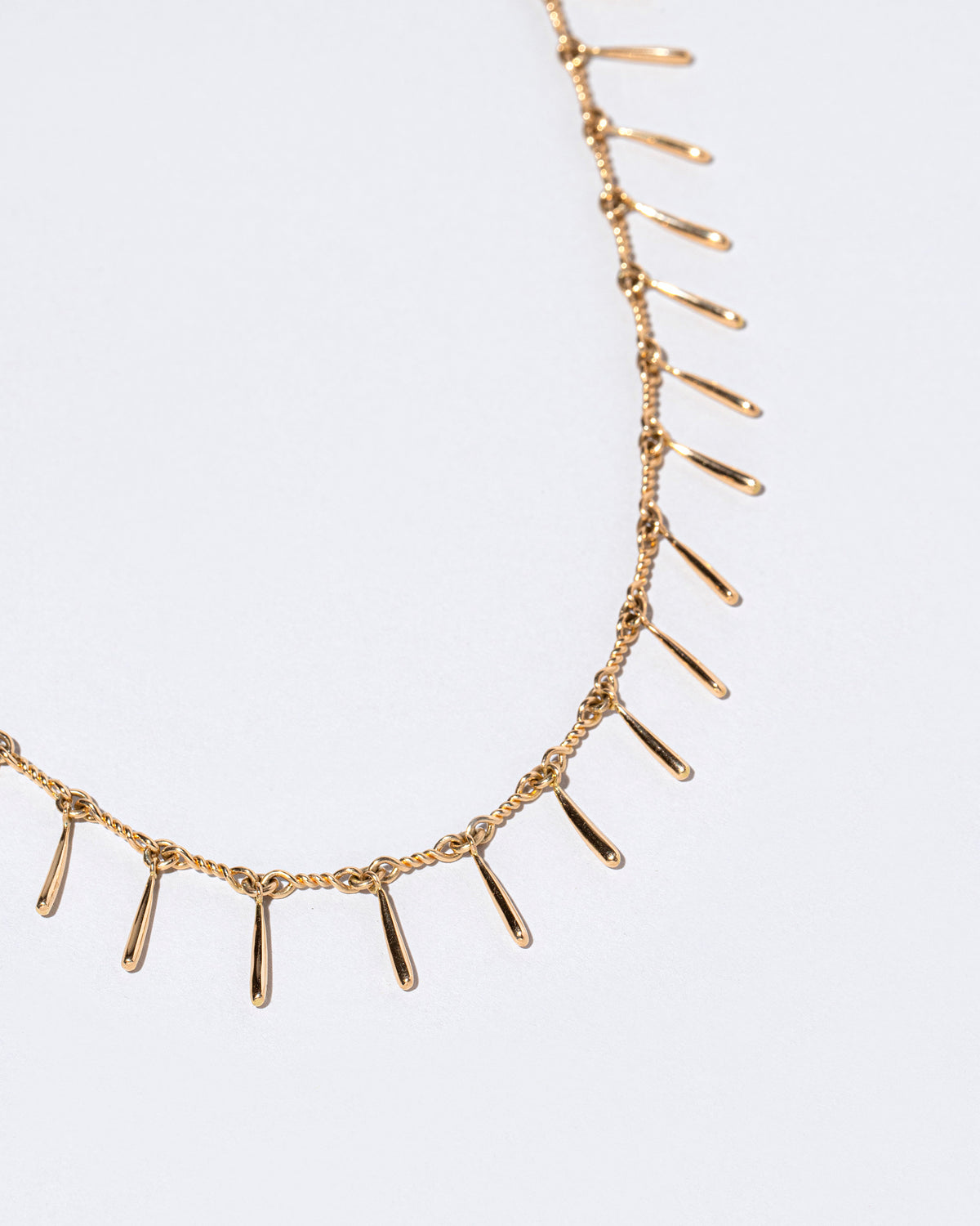 Closeup details of the Petite Swaying Necklace on light color background.
