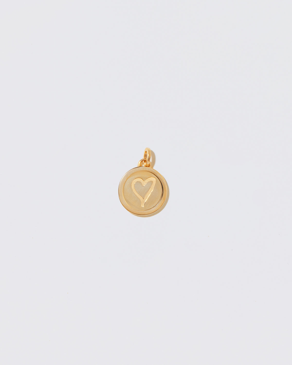 Finished Small Round Pendant Memento Pendant with engraved with a heart shape on light color background.