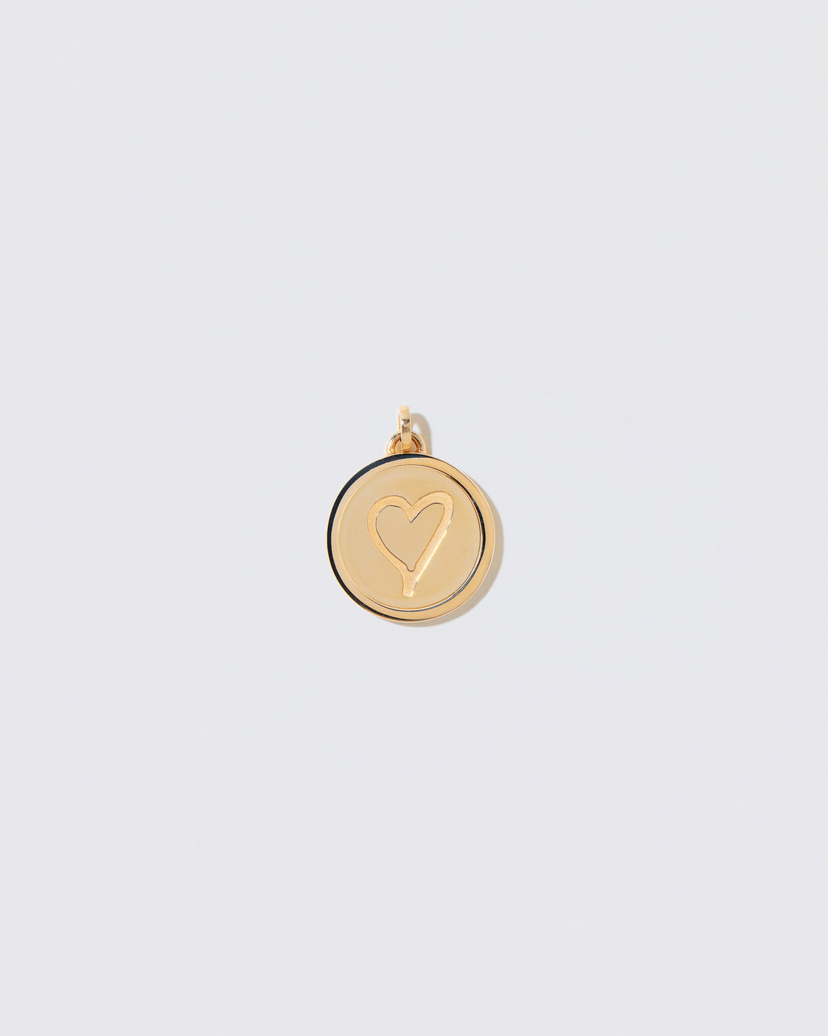 Finished Large Round Pendant Memento Pendant engraved with a heart shape on light color background.
