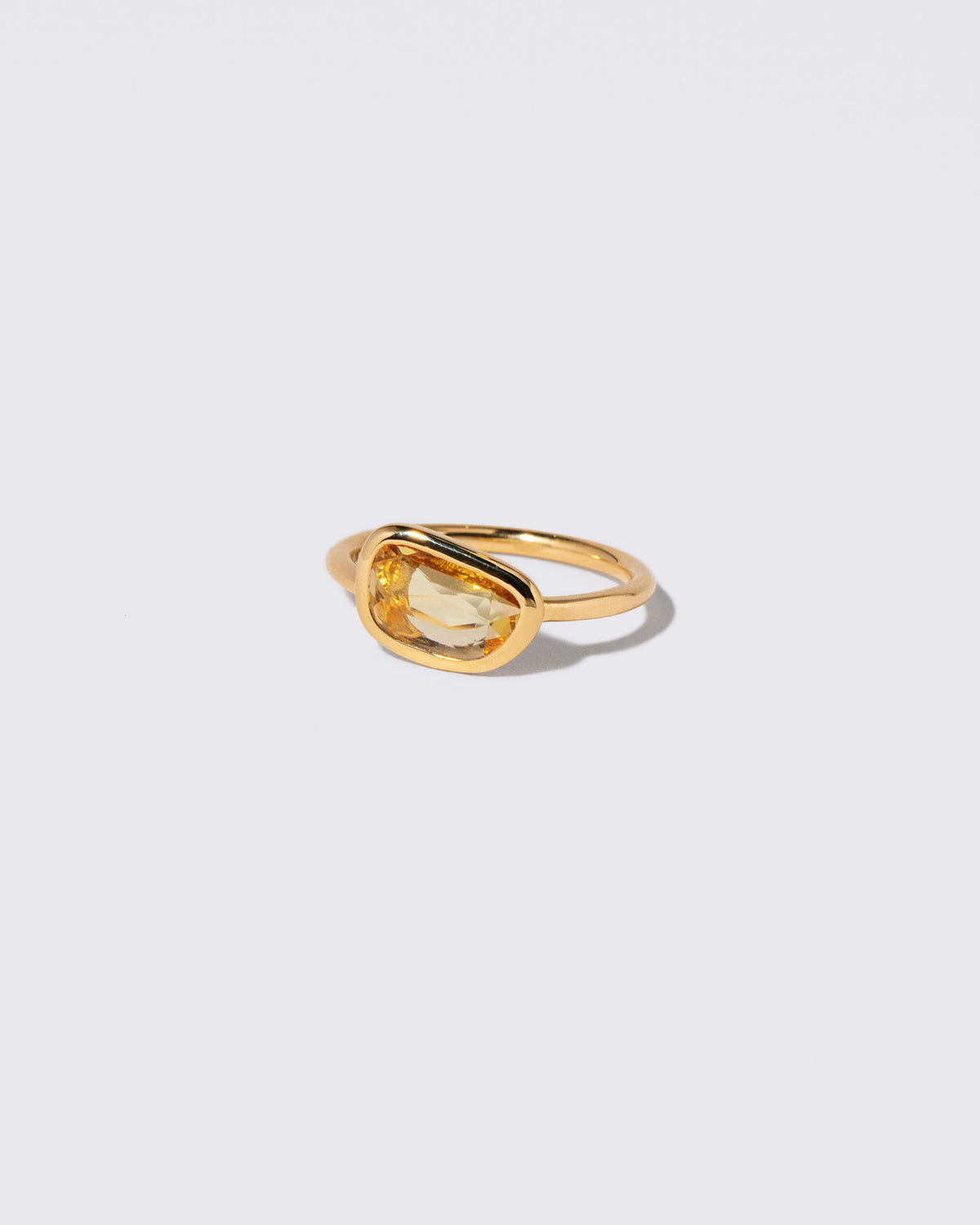View from the side of the Yellow Sapphire Gusher Ring on light color background.