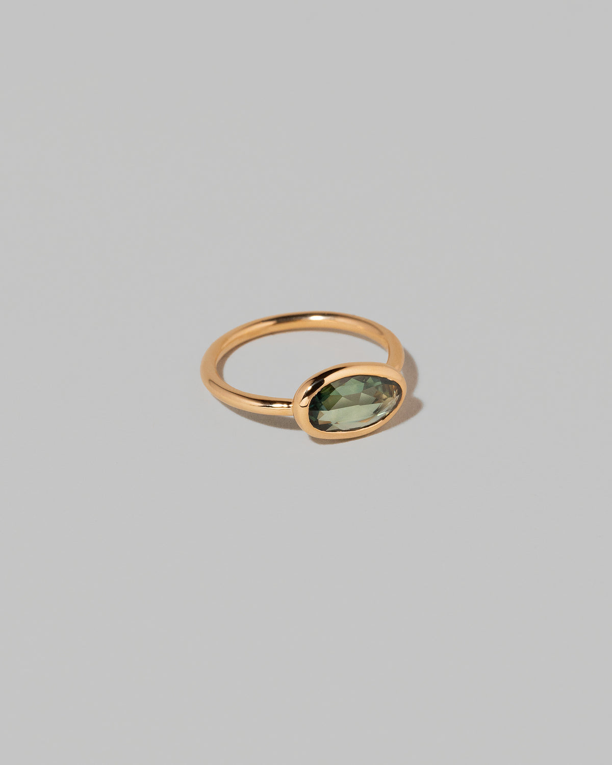 View from the side of the Gusher Green Sapphire Ring 002 on light color background.