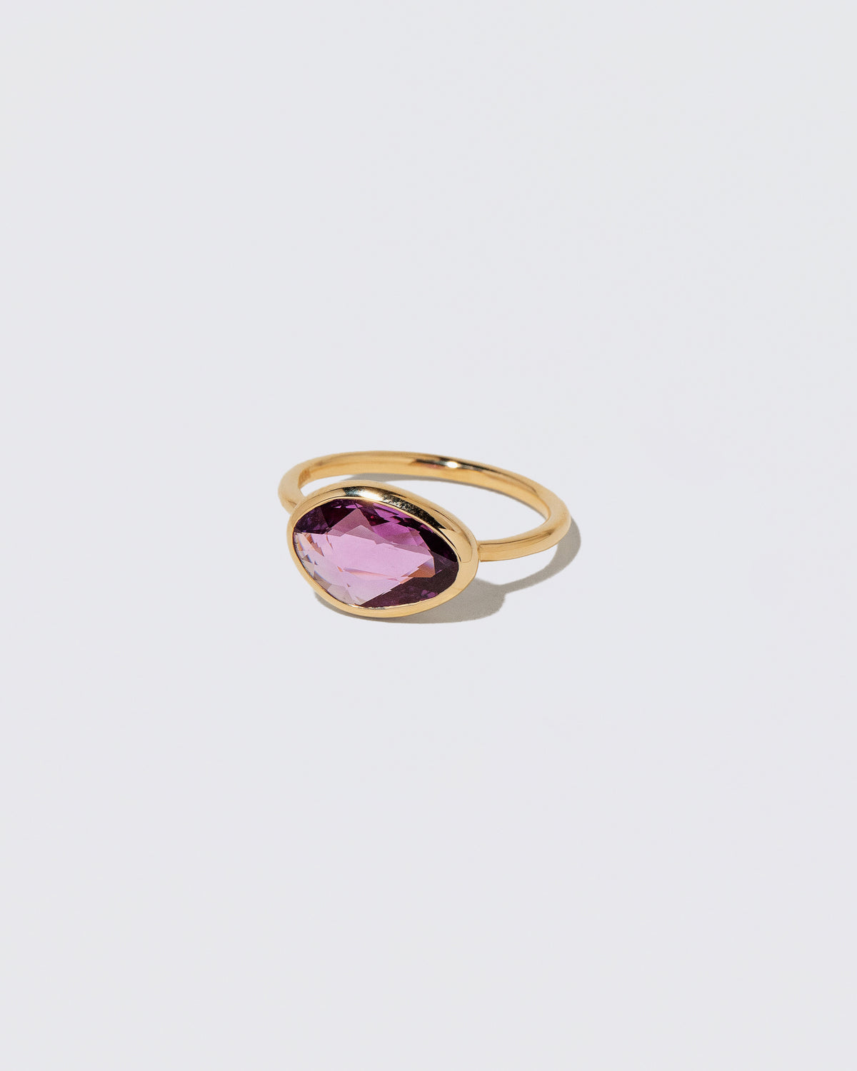 View from the side of the Gusher Pink Sapphire Ring 053 on light color background.