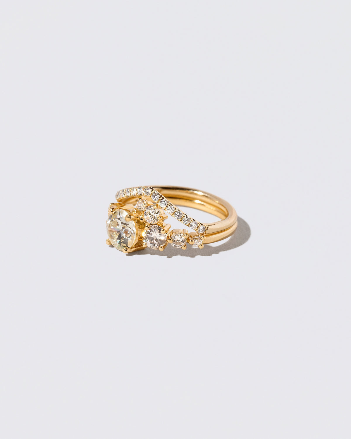 View from the side of the White Diamond Luna Ring and Gold White Diamond Pavé Luna Peak Band on light color background.