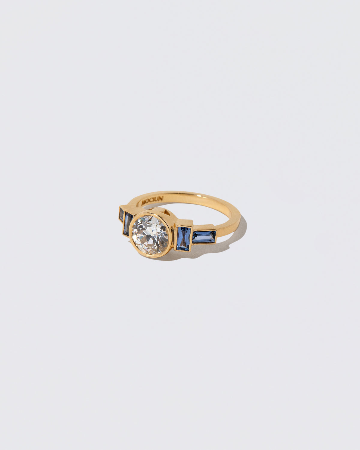 View from the side of the White Diamond & Blue Sapphire Third Eye Ring on light color background.