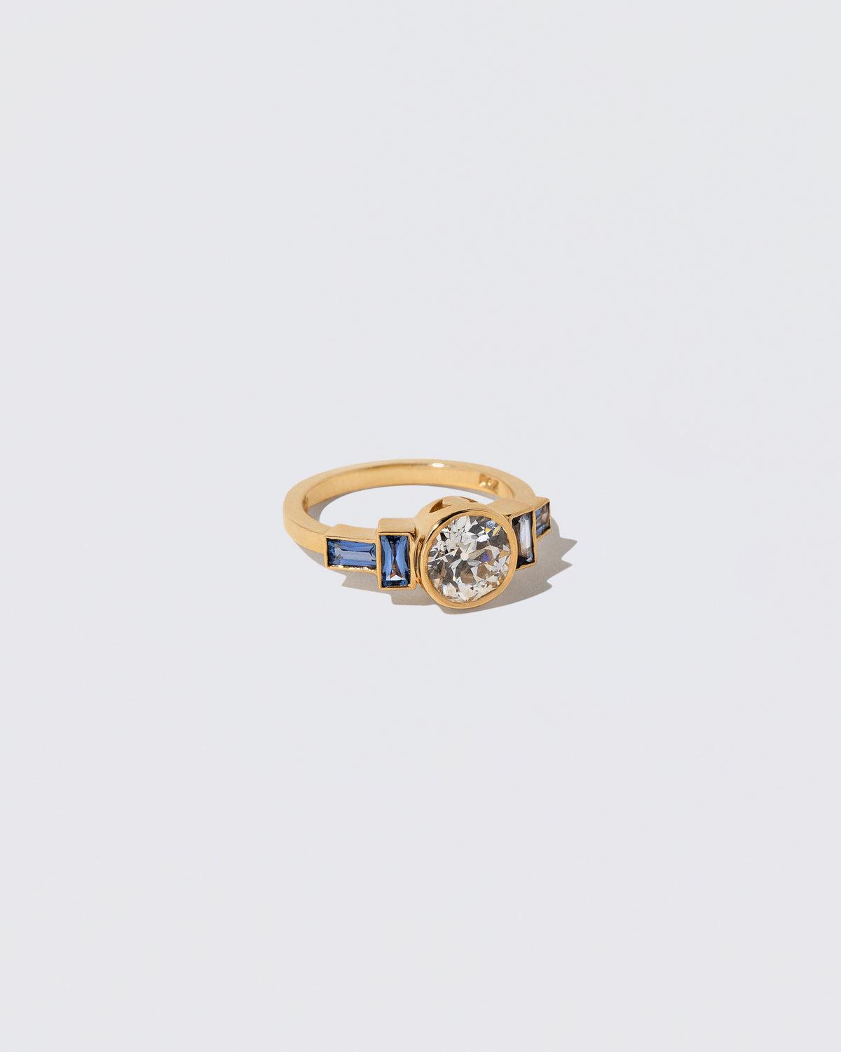 View from the side of the White Diamond & Blue Sapphire Third Eye Ring on light color background.