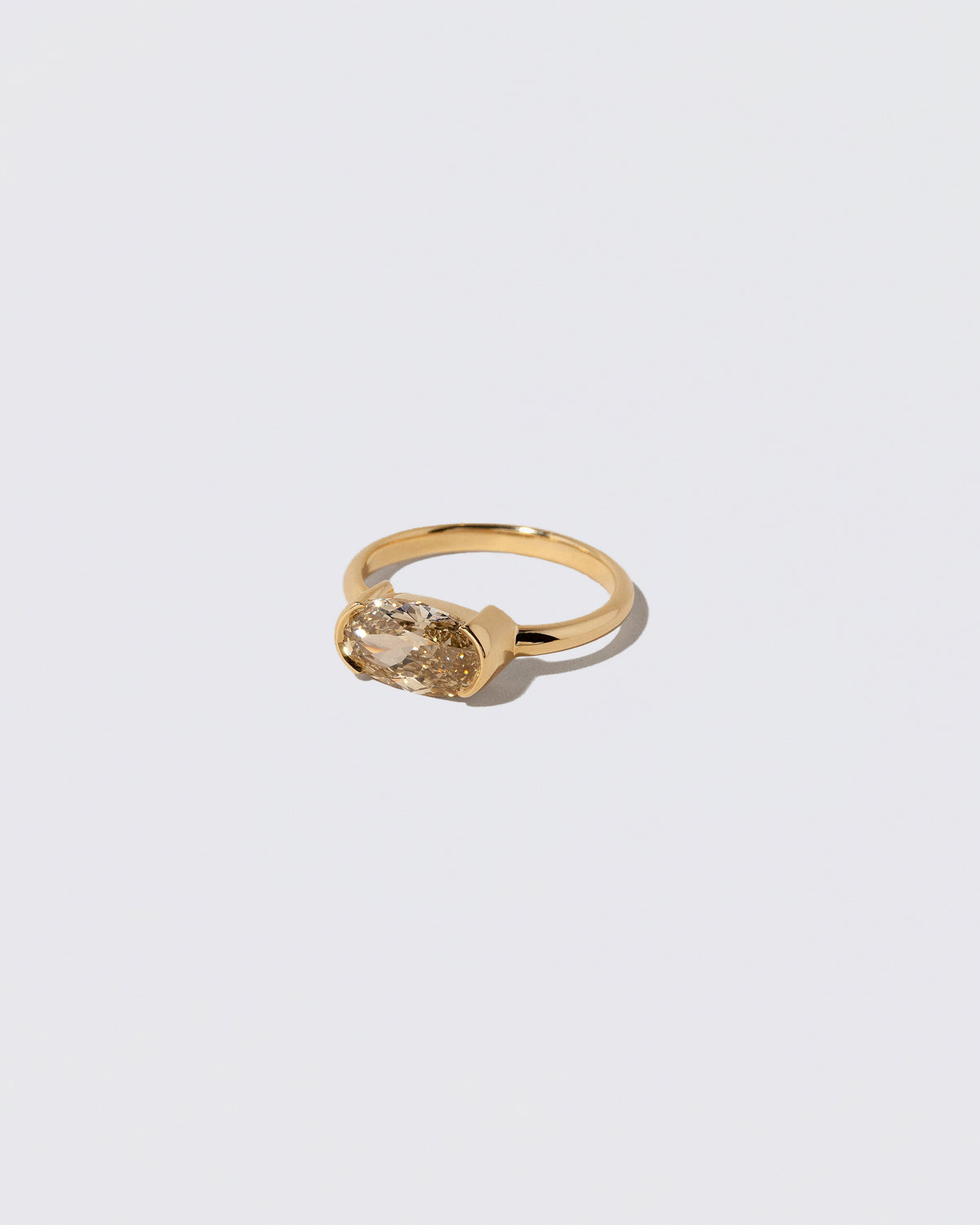 View from the side of the Oval Brown Diamond Transformation Ring on light color background.